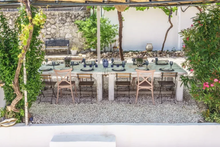 Long outdoor dining table under a vine-covered pergola