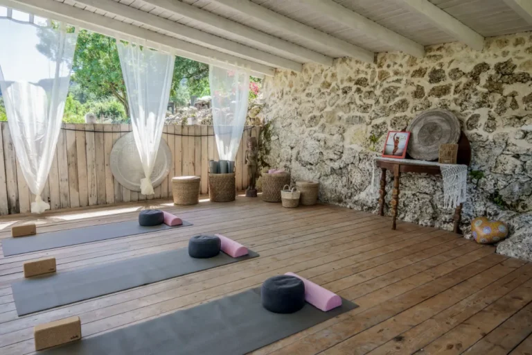 Yoga shala with natural stone wall, wooden floor, mats and bolsters