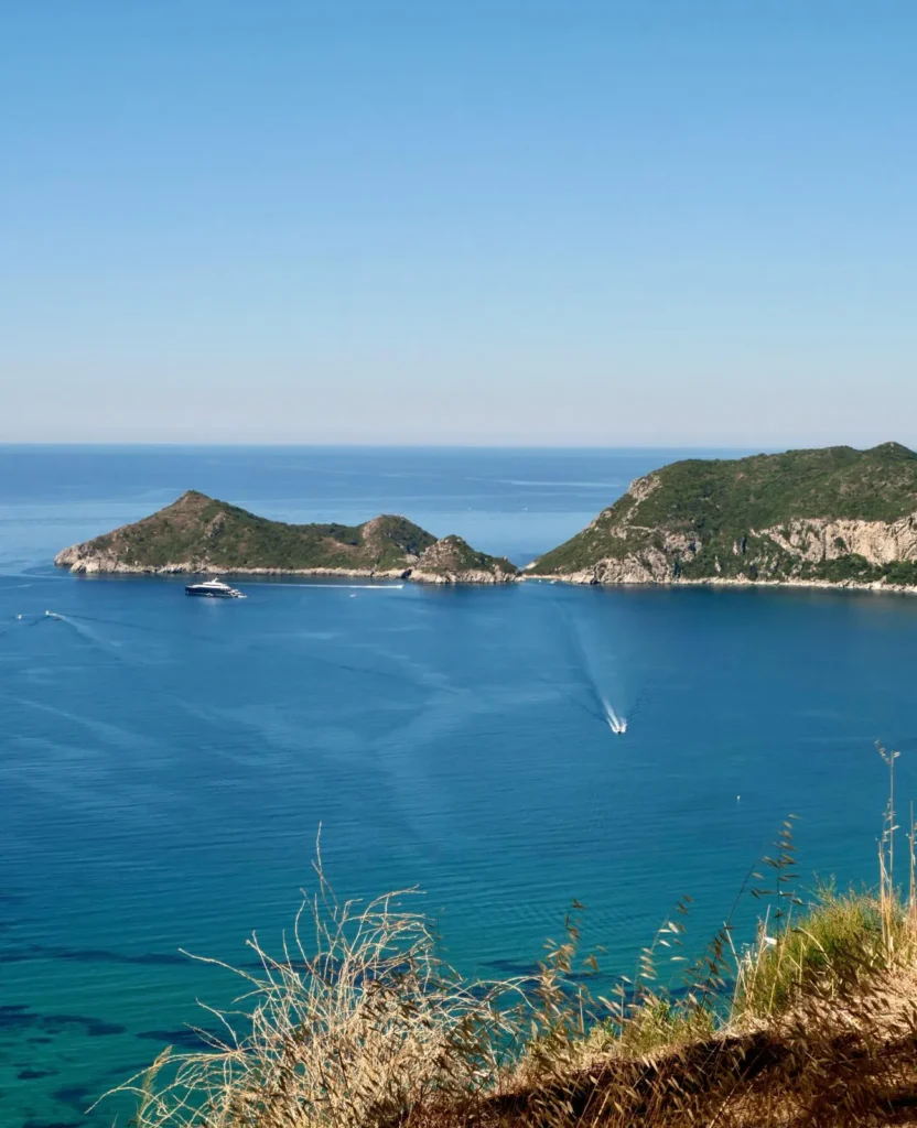 Rocky headlands and small boats on the blue water of the northwest coast of Corfu