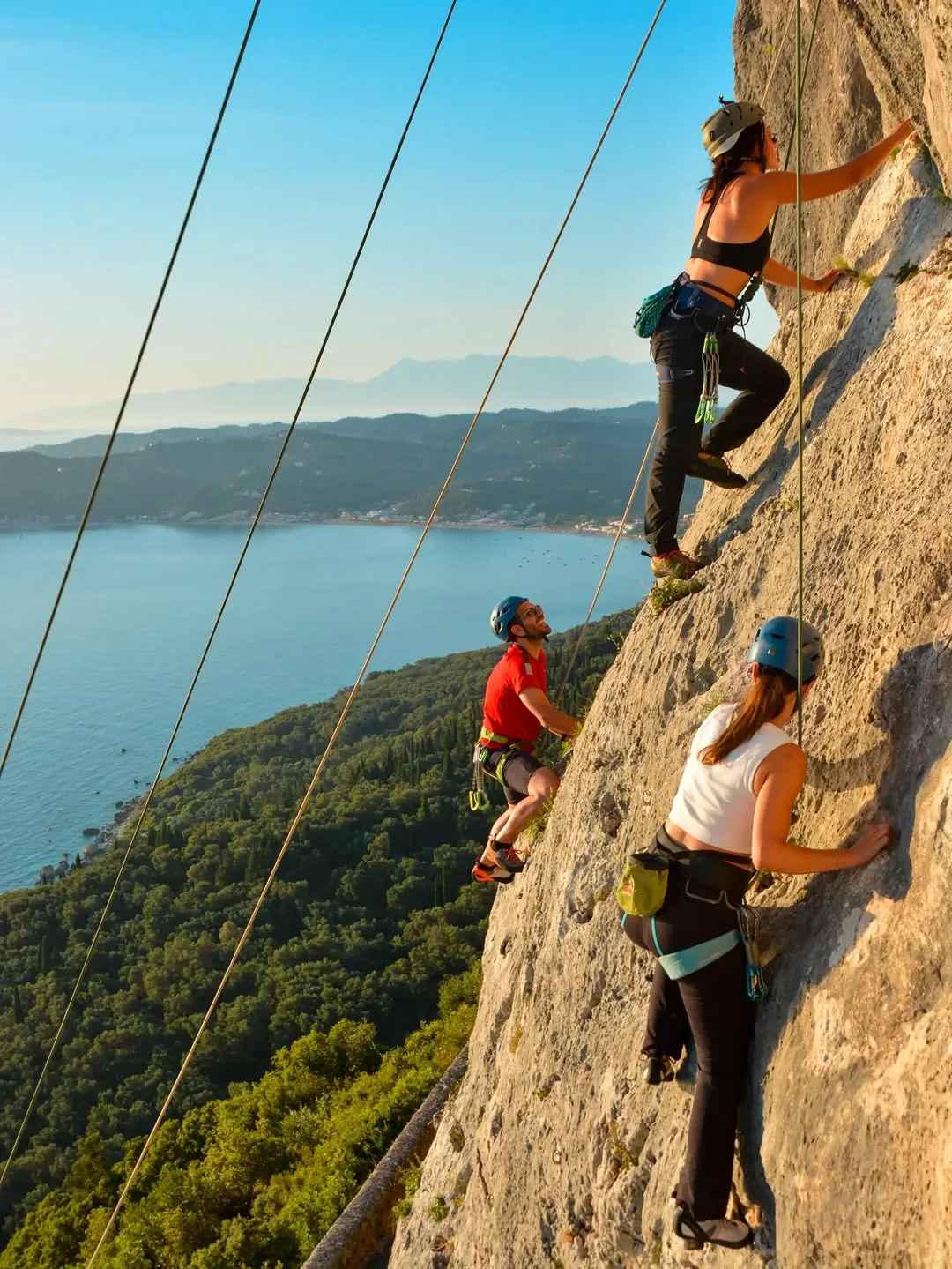 Kletternde an einer Kalksteinwand hoch über einer Bucht auf Korfu
